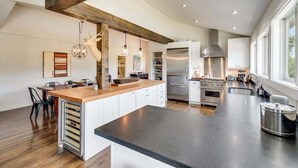 A modern kitchen with a large island, stainless steel appliances, and a wooden ceiling beam. - Calistoga Vista-Pool, Hot Tub - Tastings Included (Calistoga)