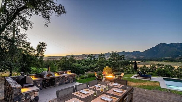 An outdoor dining area with a stone barbecue, a pool, and a view of the mountains. - Calistoga Vista-Pool, Hot Tub - Tastings Included (Calistoga)