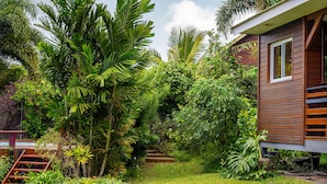A wooden house surrounded by lush greenery and a well-maintained garden with a wooden staircase leading up to the house. - Wooden bungalow Ti Briz - Au jardin d'Éole (Sainte-Rose)