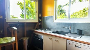 A compact kitchen with a gas stove, sink, and a dishwashing machine. - Wooden bungalow Ti Briz - Au jardin d'Éole (Sainte-Rose)
