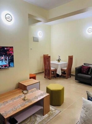 Cozy living space with a dining area and seating area, featuring a wooden table and two chairs, a sofa, and an ottoman.