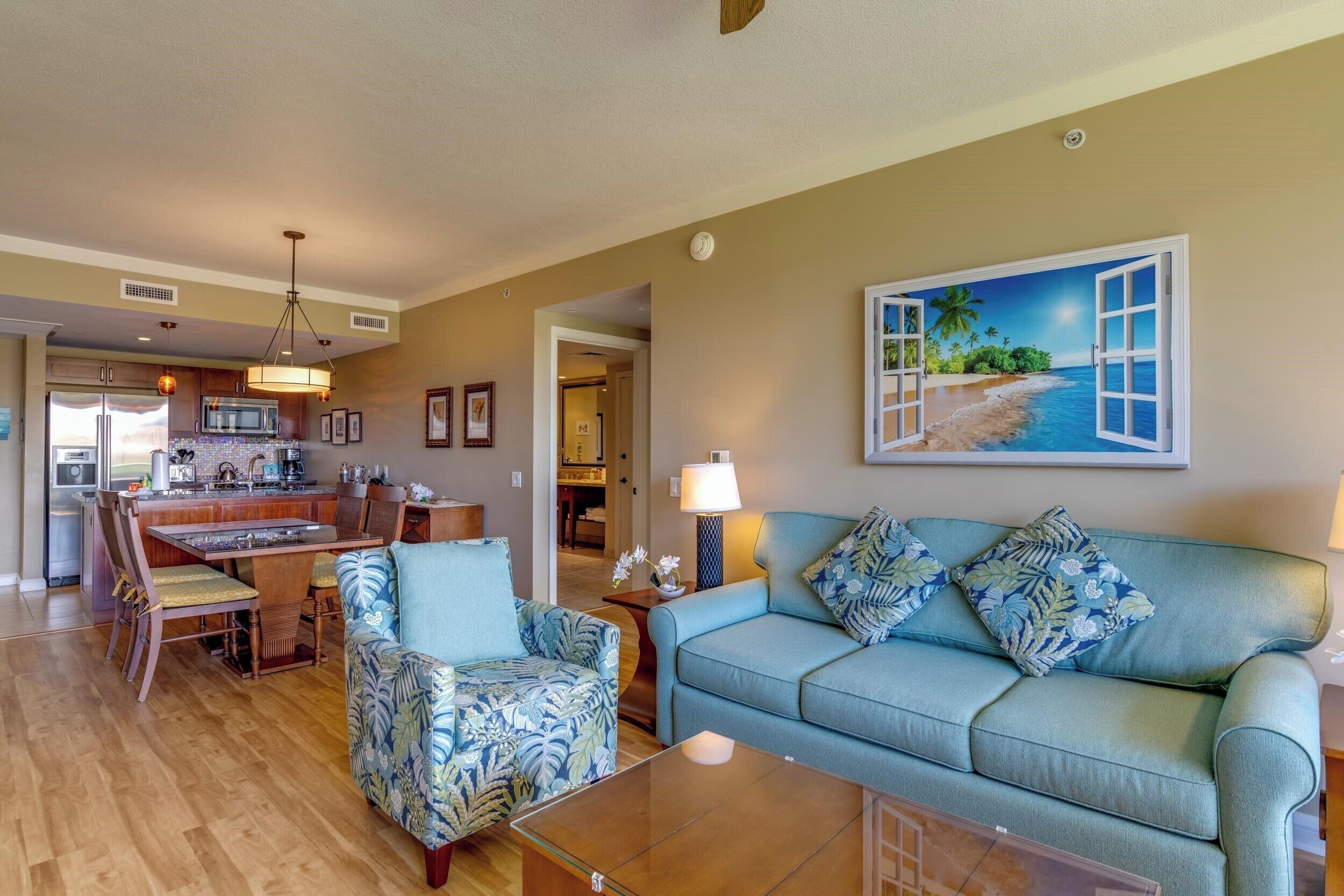 A living room with a sofa, armchairs, a coffee table, and a painting of a beach scene.