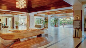 A spacious lobby with a wooden boat display, large windows, and a sign listing amenities like a general store and fitness room.