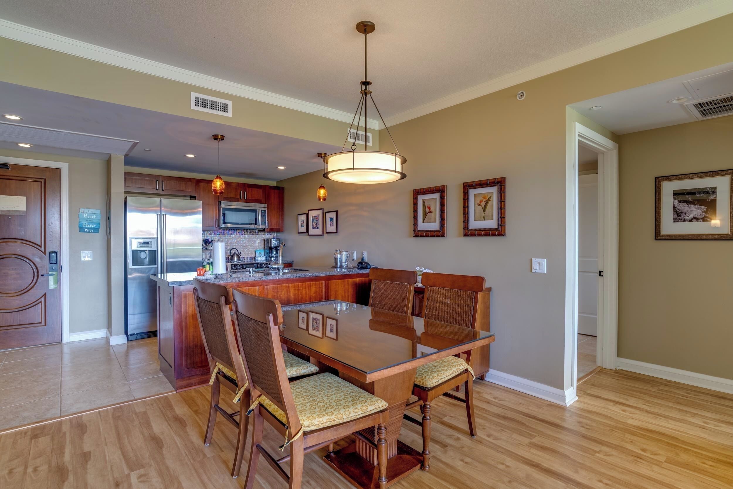 A spacious kitchen with wooden cabinets, a central island, and a dining area with a glass-top table and chairs.