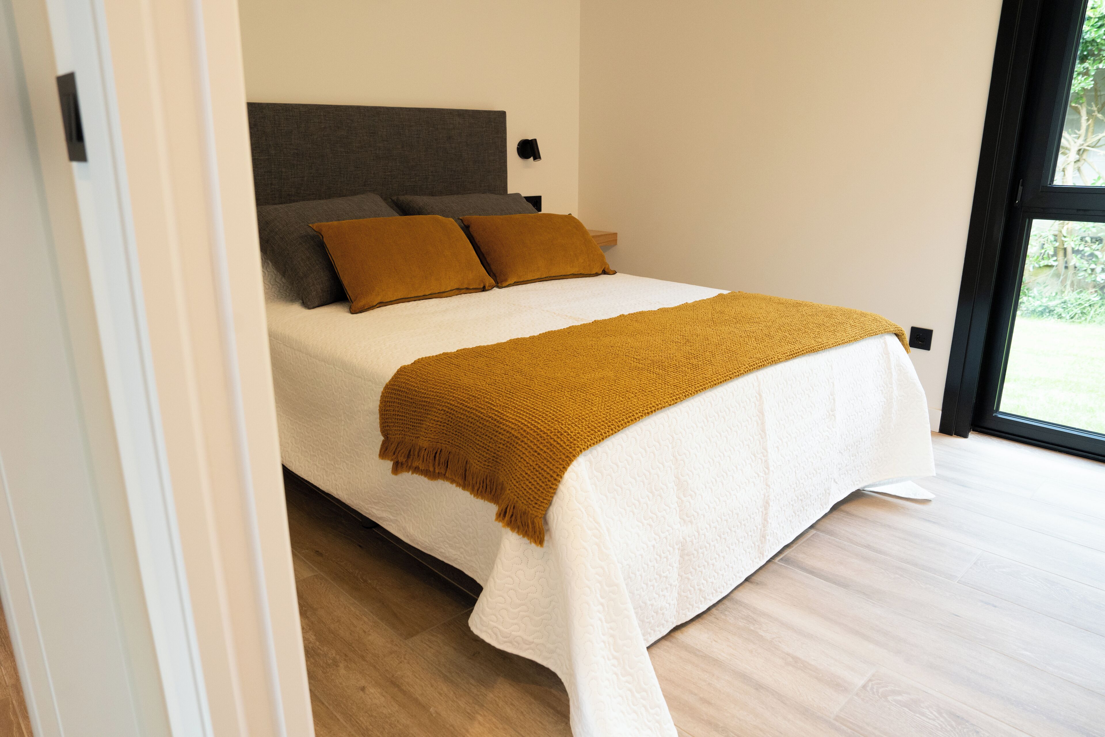 Een moderne slaapkamer met een bed, kussens en een raam.