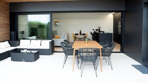 A modern outdoor living area with a wooden table and chairs, a sofa, and a coffee table. - Balcobo Villas&Cabañas (Arteixo)