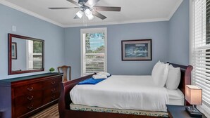 A bedroom with a bed, a dresser, a ceiling fan, a window with blinds, and a framed picture on the wall. - Capes Cottage | 1BR Near Rosewood (Columbia)
