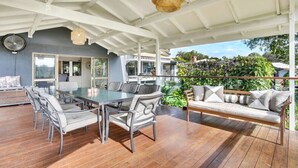 An outdoor patio with a dining table and chairs, a sofa, and a hanging light fixture.