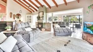A spacious living room with a fireplace, grey sofas, and a large TV.