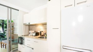 A modern kitchen with white cabinetry, a built-in oven, and a stainless steel sink.