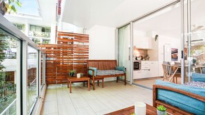 A modern apartment with a balcony, wooden furniture, a kitchen, and a view of the city.
