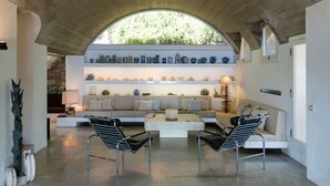 A modern living room with a white sofa, two black and white chairs, a coffee table, and a wall of decorative vases.