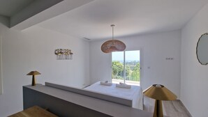 Une chambre moderne dotée d’une grande fenêtre, d’un ventilateur de plafond et d’une œuvre d’art accrochée au mur.