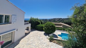 Une maison moderne dotée d’une terrasse en pierre, d’une piscine et offrant une vue sur la mer.