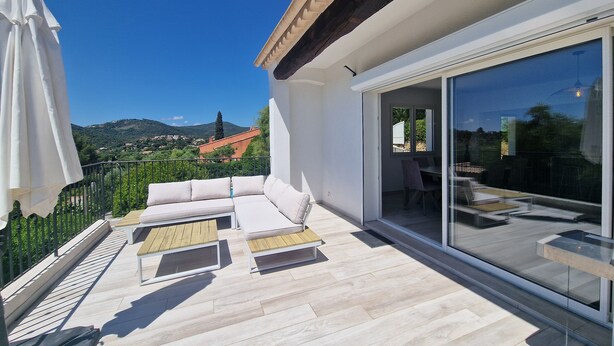 Un espace de vie extérieur moderne comprenant un canapé, une table à manger et une porte vitrée donnant sur un patio.