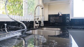 Una cocina con un lavamanos de acero inoxidable, un escurreplatos y un microondas.