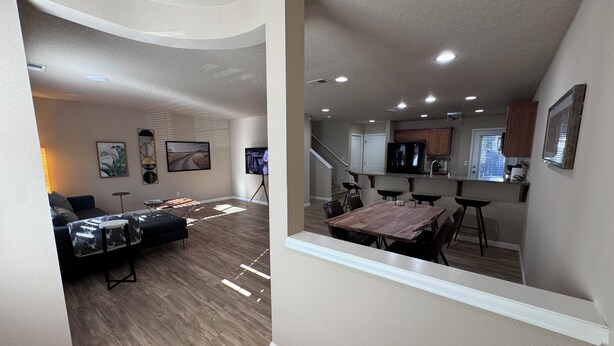 A modern open-plan living area with a dining table and chairs, a sofa, and a TV.