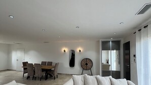 Un salon spacieux comprenant un grand canapé, une table basse et un coin repas avec une table et des chaises.