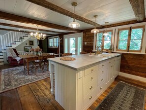 Una cocina amplia con una isla grande, vigas de madera y vistas al exterior a través de las ventanas.