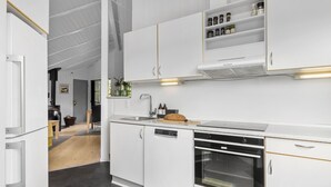 A modern kitchen with white cabinetry, a built-in oven, and a countertop with a bread loaf.