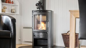 A modern living room with a black wood-burning stove, a white radiator, and a black leather chair.