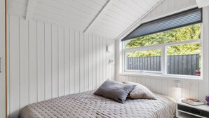 A bedroom with a bed, a window with a view of greenery, and a white ceiling.