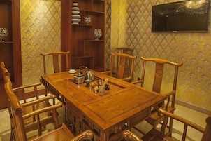Una mesa de comedor de madera tradicional con sillas, una estantería con vajilla y un televisor montado en la pared.