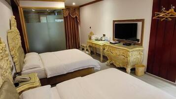 A hotel room with two beds, a desk with a television, and a mirror.