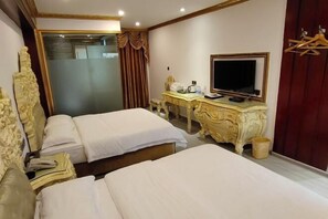 Ein Hotelzimmer mit zwei Betten, einem Schreibtisch, einem Fernseher und einem Spiegel.