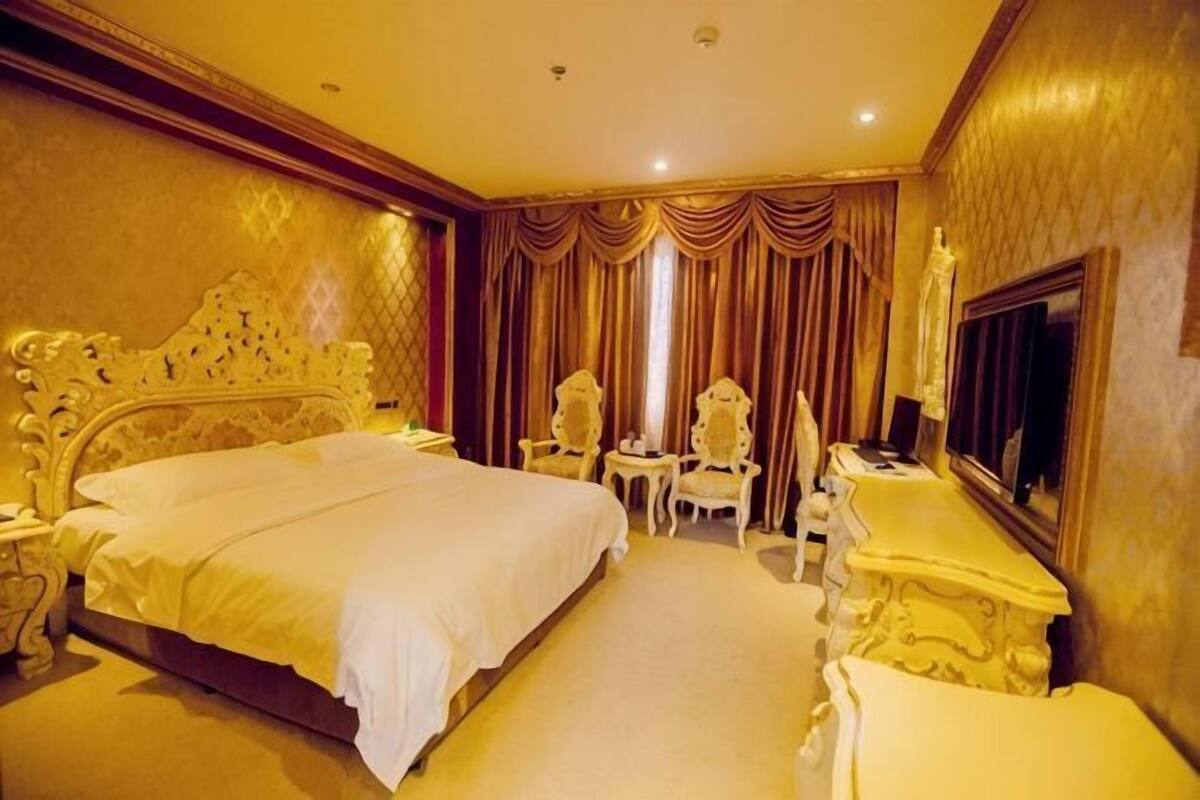 Habitación de hotel con una cama grande, dos sillones, una mesita y un espejo.
