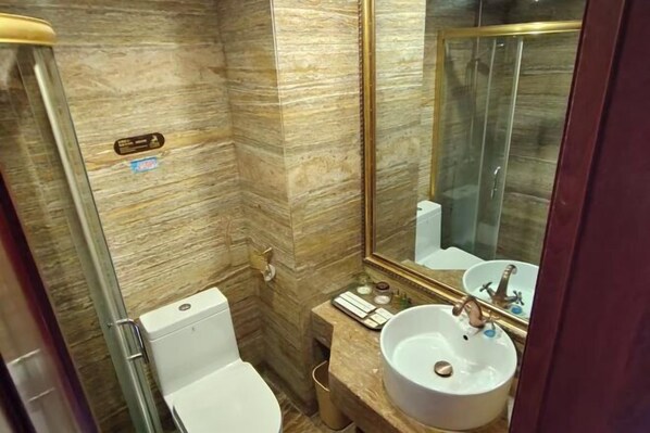 Ein Badezimmer mit Marmorwand, Waschbecken in Weiß und einer Duschkabine aus Glas.