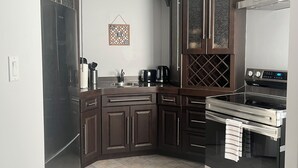 A modern kitchen with dark wooden cabinets, a stainless steel range hood, and a built-in oven. - Serene & Luxurious  basement apartment. (Timmins)