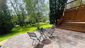 A patio with hexagonal tiles, two chairs, and a small table. - Serene & Luxurious  basement apartment. (Timmins)