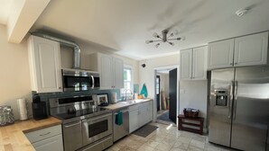 A modern kitchen with stainless steel appliances, white cabinets, and a tiled floor.