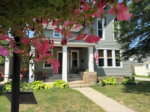 A residential house with a front porch, a flag, and a well-maintained lawn.