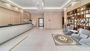 A hotel lobby with a reception desk, seating area, and a decorative wall with shelves. - Chuangejia Yuerongzhuang Hotel (Yongkang East Bus Station Exhibition Center) (Yongkang)