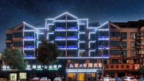A hotel with multiple floors, illuminated signage, and a parking lot with several cars. - Chuangejia Yuerongzhuang Hotel (Yongkang East Bus Station Exhibition Center) (Yongkang)