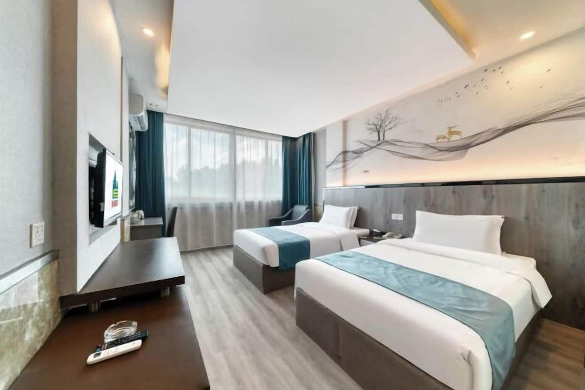 Une chambre d’hôtel avec deux lits, un bureau, une télévision et une grande fenêtre.