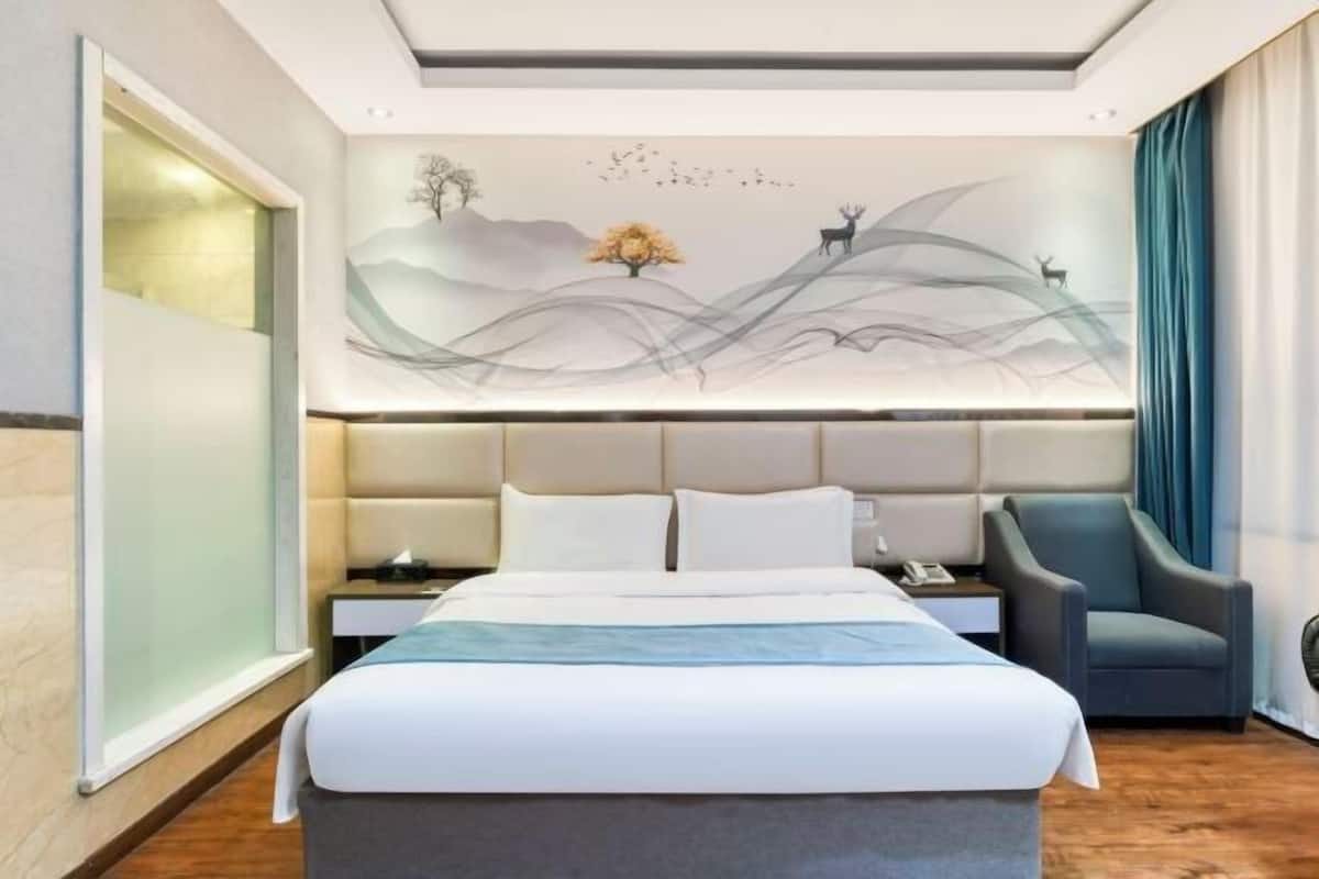 Une chambre d’hôtel moderne avec un grand lit, une table de chevet, une chaise et une fresque murale.