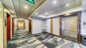 A hotel corridor with a patterned carpet, an elevator, and a small table with a vase. - Chuangejia Yuerongzhuang Hotel (Yongkang East Bus Station Exhibition Center) (Yongkang)