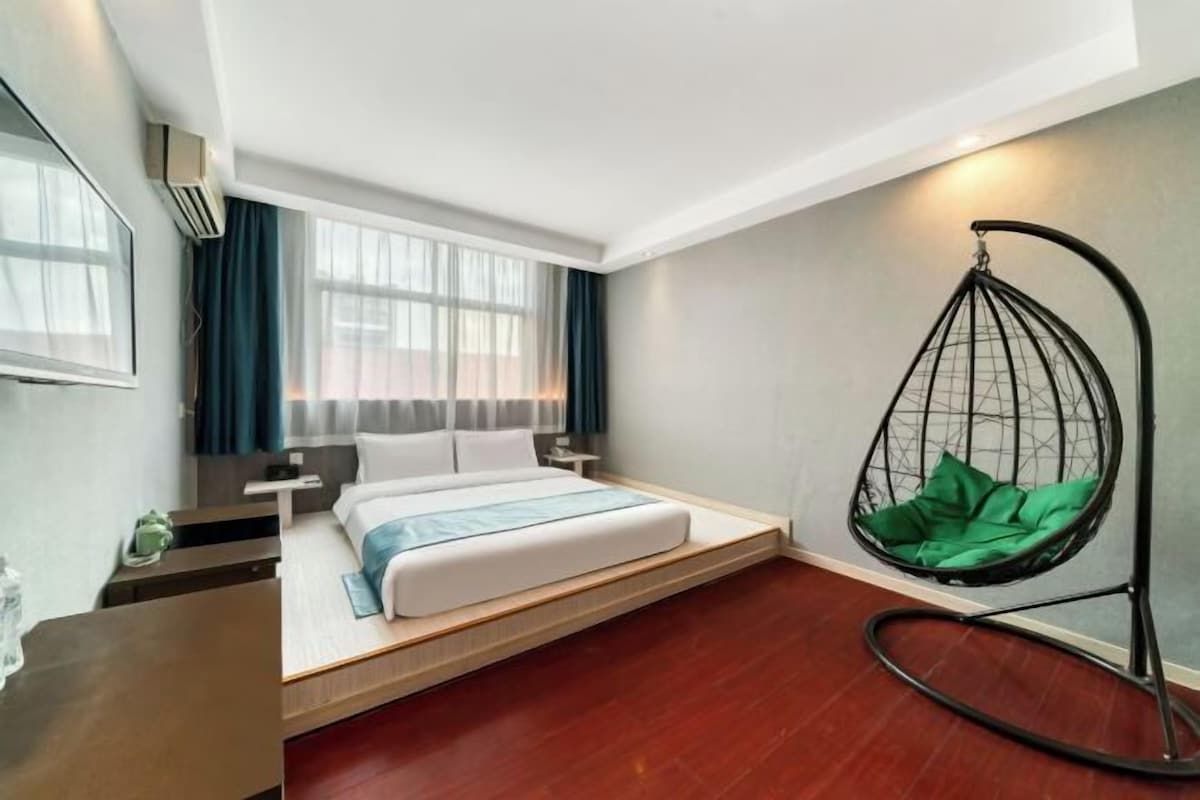 Una habitación de hotel moderna con una cama, un sillón colgante y un escritorio pequeño.