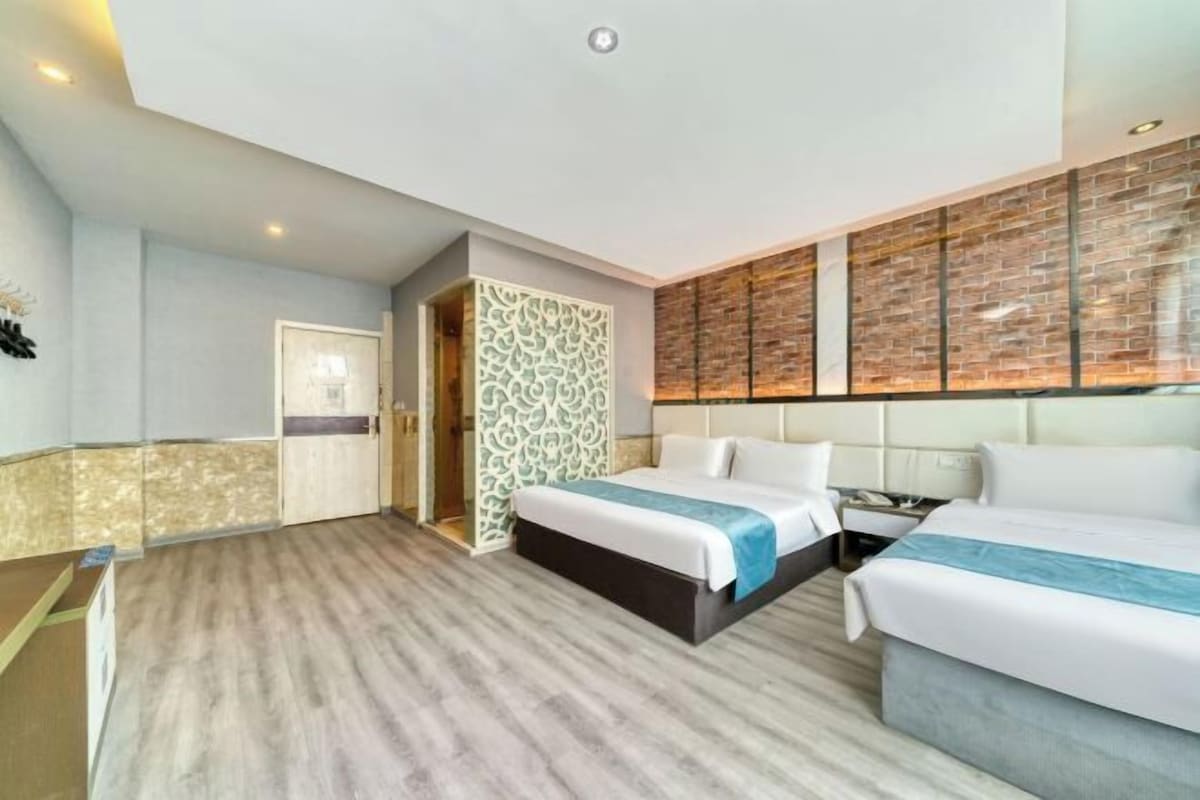 Habitación de hotel con dos camas, un papel tapiz estampado y una pared de ladrillo.