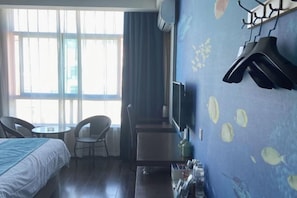 A hotel room with a bed, a desk, a chair, a TV, and a wall with an underwater mural. - Chuangejia Yuerongzhuang Hotel (Yongkang East Bus Station Exhibition Center) (Yongkang)