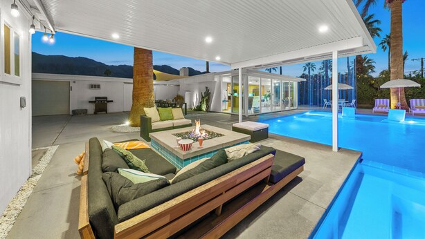 Un espace de vie extérieur moderne comprenant une piscine, des sièges et un foyer.