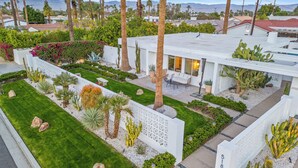 Une maison moderne dotée d’un jardin bien entretenu, comprenant des cactus et des palmiers, ainsi que d’un espace patio.