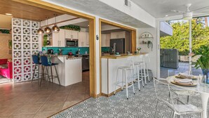 Une cuisine moderne dotée d’un îlot central, de tabourets de bar et d’un coin repas avec une table en verre.