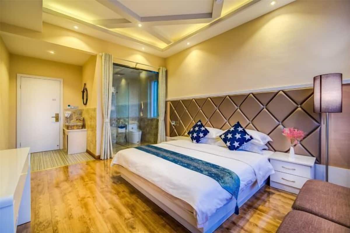 A hotel room with a bed, bedside table, and a view of the outside.