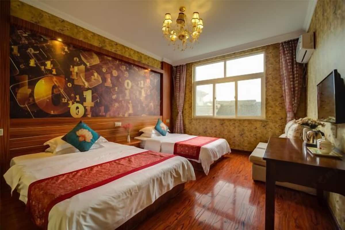A hotel room with two beds, a chandelier, a large window, and a television.