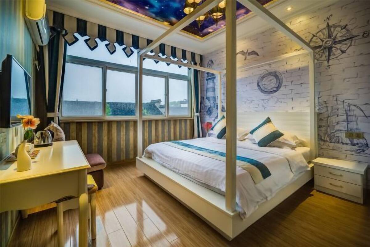 A room with a bed, a desk, a window, and a wall with a compass and map.