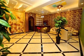A lobby with a checkered floor, a reception desk, and a seating area with a potted plant. - Wuzhen Flower House (Tongxiang)